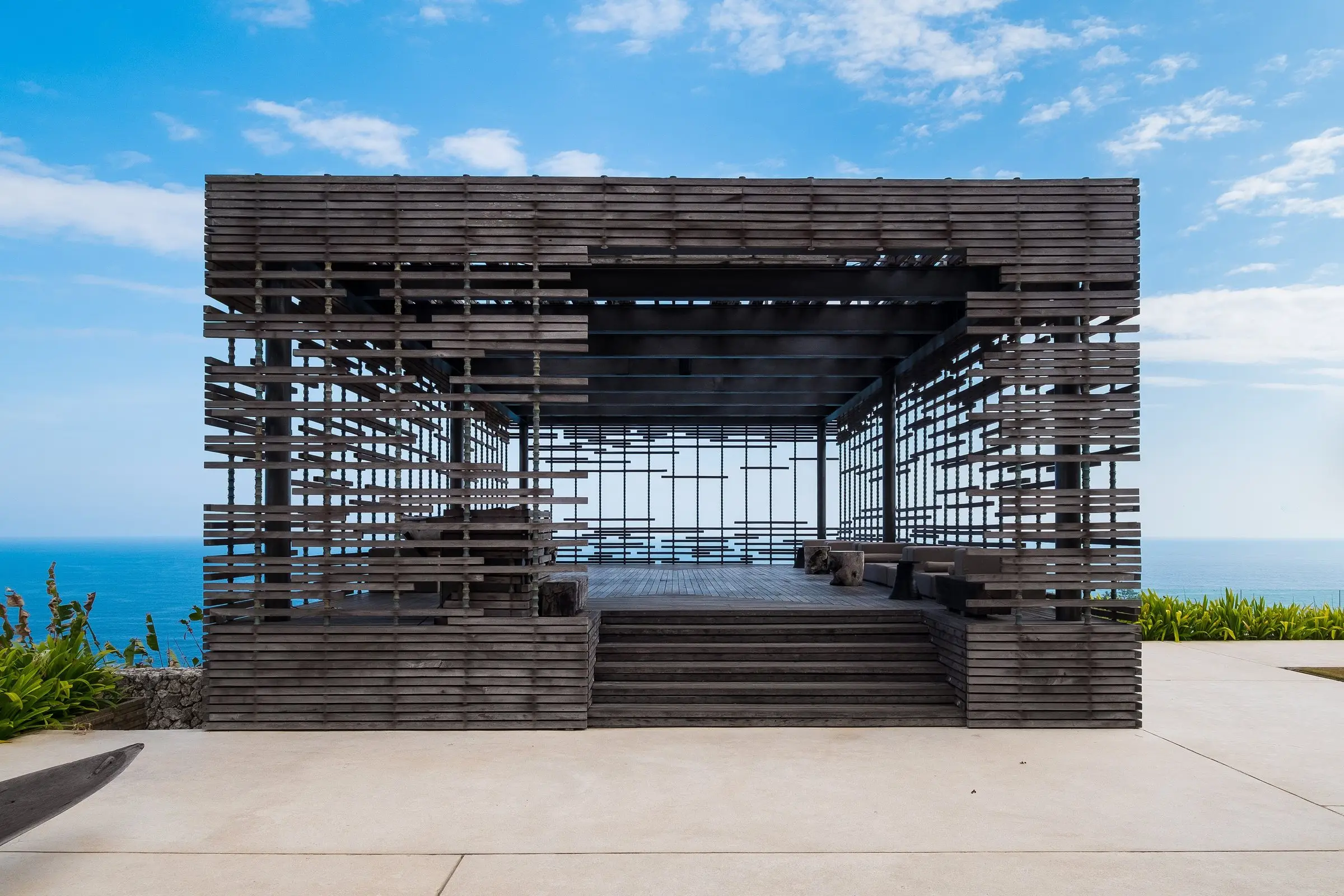 Open timber pavilion on a cliff edge facing the ocean